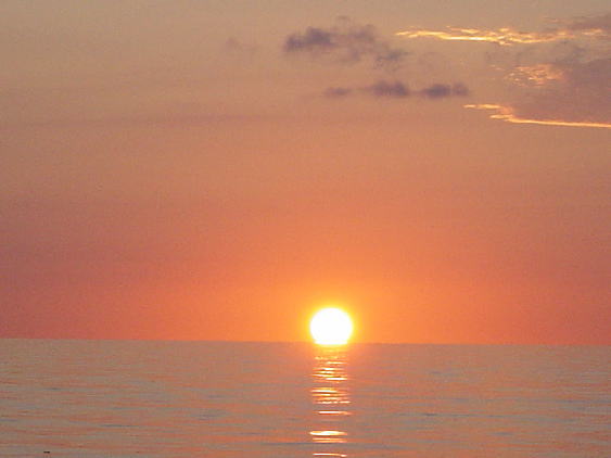 海に沈み行く夕日の写真。海上にて